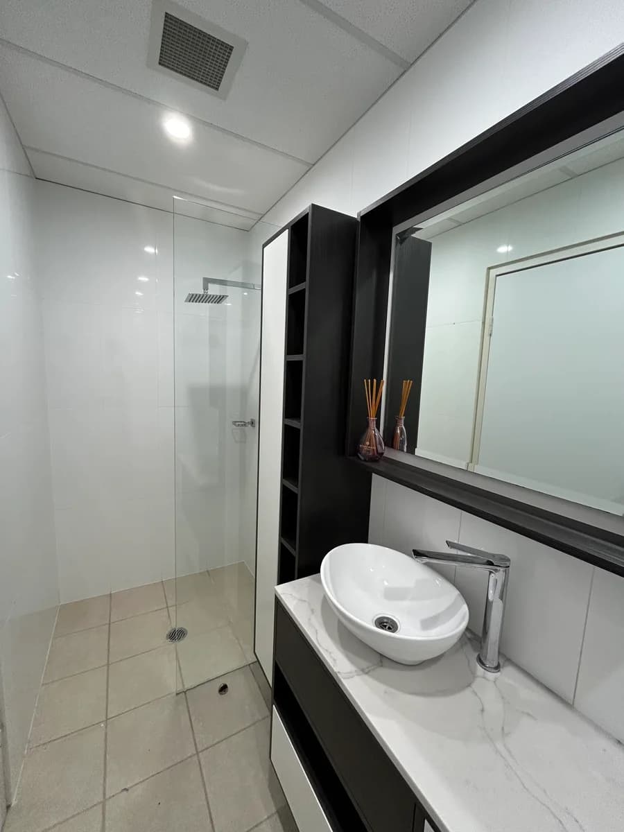 Finished commercial bathroom with shower, vanity and black shelving